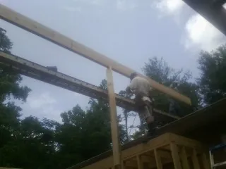 Carpenter setting a ridge beam over a new addition frame — Ice Dam Removal by Roofing Brothers in Ellerbe