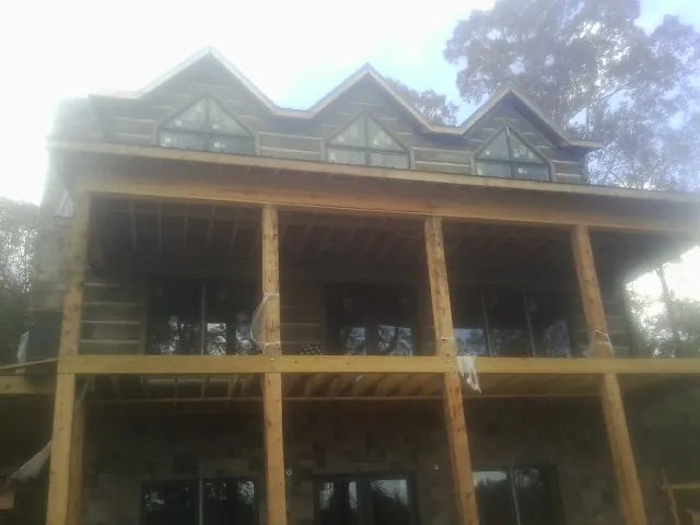 Dormers and porch framing on a large log home under construction — Roof Coating work by our crew in Ellerbe