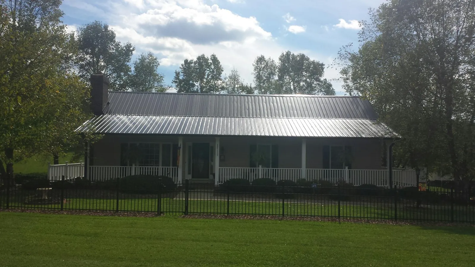 Gray metal roof on a brick ranch with a full width front porch — Gutter Guard Installation work by our crew in Ellerbe